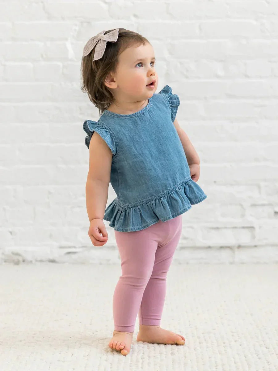 Toddler wearing Anya Chambray Ruffle Hem Top with ruffle sleeves.