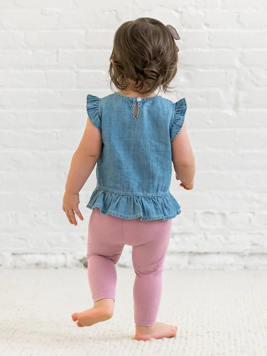 Toddler wearing Anya Chambray Ruffle Hem Top with ruffle sleeves and hem.