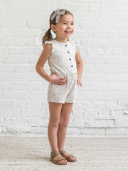 Girl wearing Shaye Romper with coconut buttons and flutter sleeves, made of organic cotton.