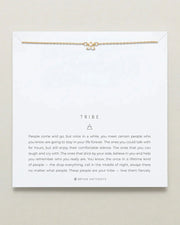 TRIBE DAINTY friendship necklace on display card, featuring an adjustable brass chain with a small pendant, available in 14k gold and silver finishes.