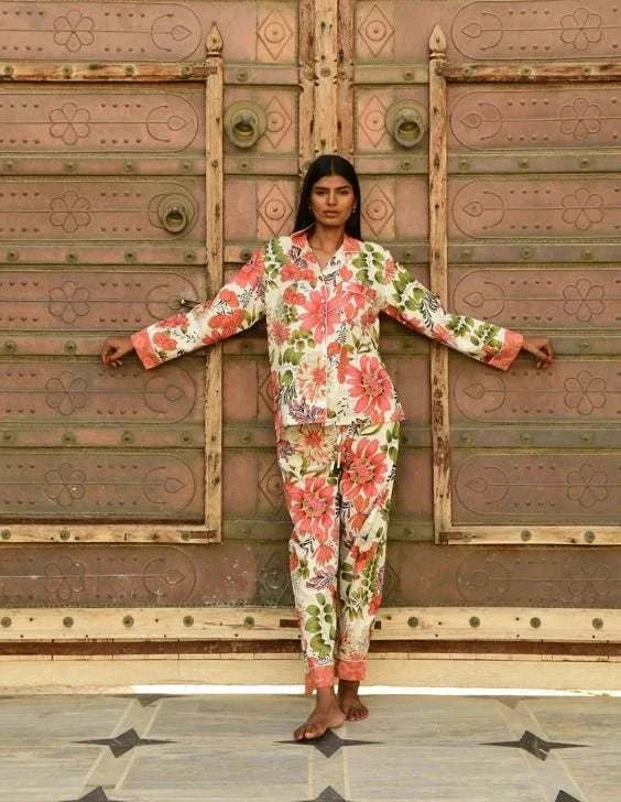 Woman wearing Buddha Bouquet PJ's with floral print in front of ornate wooden doors.