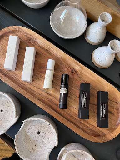 Organic roll-on oil perfumes with pure essential oils on a wooden tray.